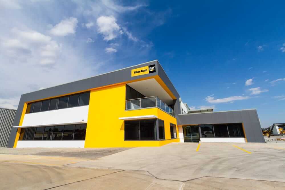 Caterpillar: Industrial Anti Slip Floor Coating Solutions showroom exterior under blue sky with bright yellow facade.
