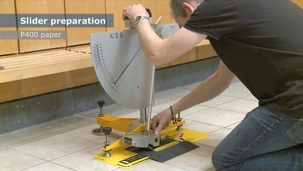 Slider preparation for slip resistance testing using P400 paper on tile surface.