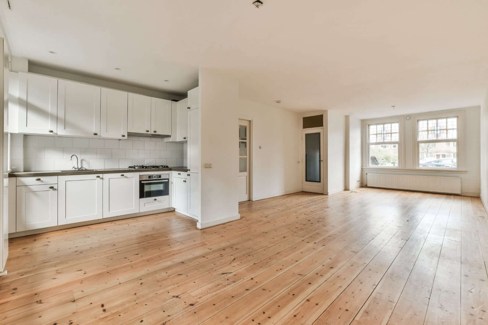 Modern kitchen interior featuring non-slip floor paint, highlighting spacious wooden flooring and bright colors.