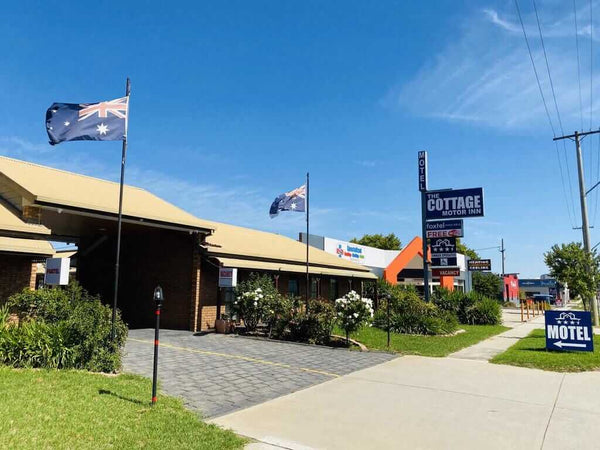 Stellmann makes showers slip-resistant at The Cottage Motel Inn exterior view with flags and signage in Albury.