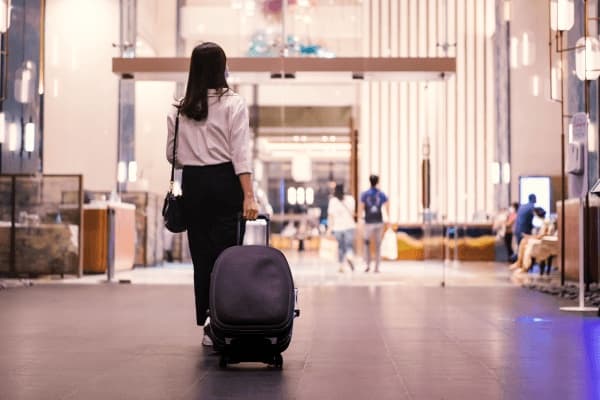 A traveler with a suitcase entering a modern hotel lobby, showcasing stylish interior design.