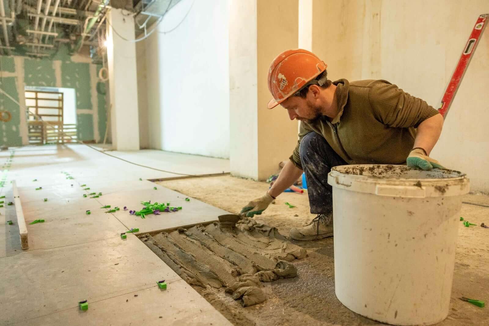 Tradies applying non-slip floor coating for safer surfaces in a construction area.