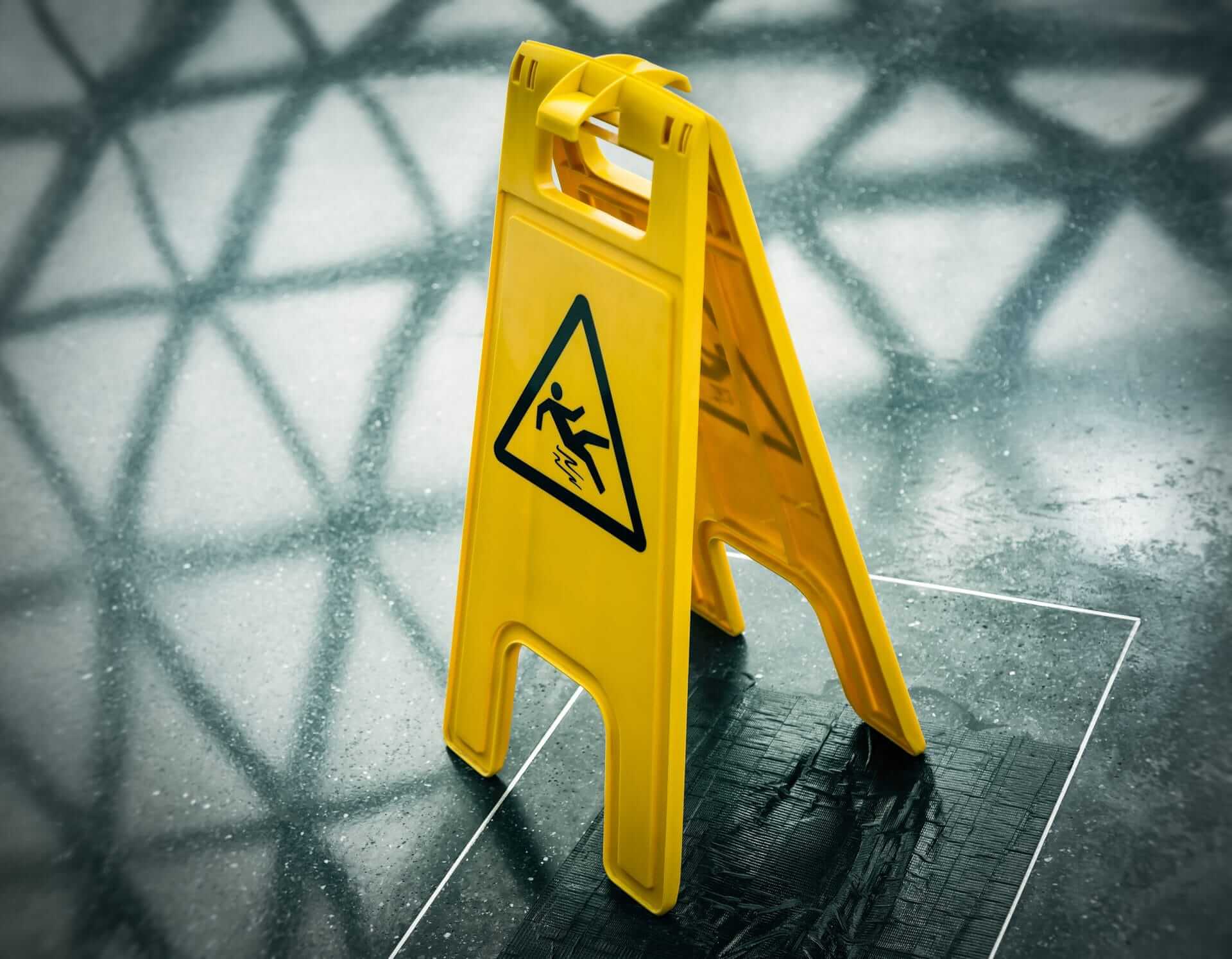Caution wet floor sign on a shiny surface highlighting slip hazards and importance of non-slip solutions.
