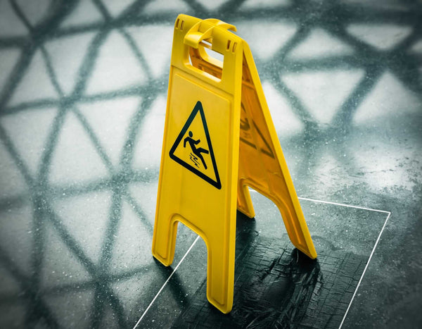 Caution wet floor sign on a shiny surface highlighting slip hazards and importance of non-slip solutions.