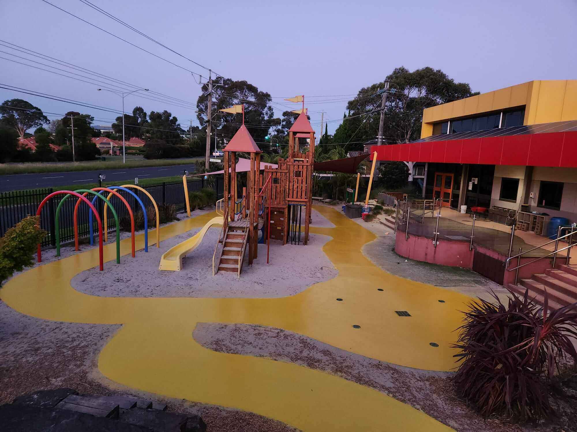 Outdoor childcare play area with bright yellow Stellmann anti-slip coating, enhancing safety and visual direction for kids and carers